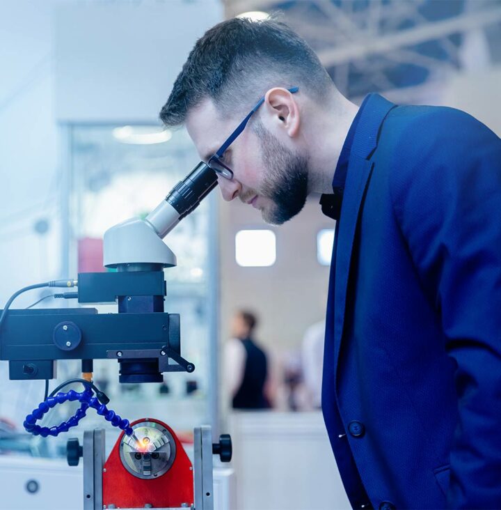 A scientist analyzing powder metals in a laboratory using precision microscopy equipment.